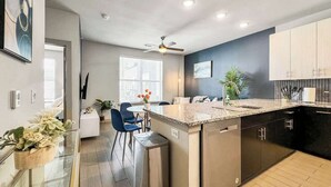 Una cocina moderna con una isla central, una zona de comedor con sillas y un ventilador de techo.