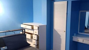 Een slaapkamer met een bed, een dressoir, een kast en een spiegel.