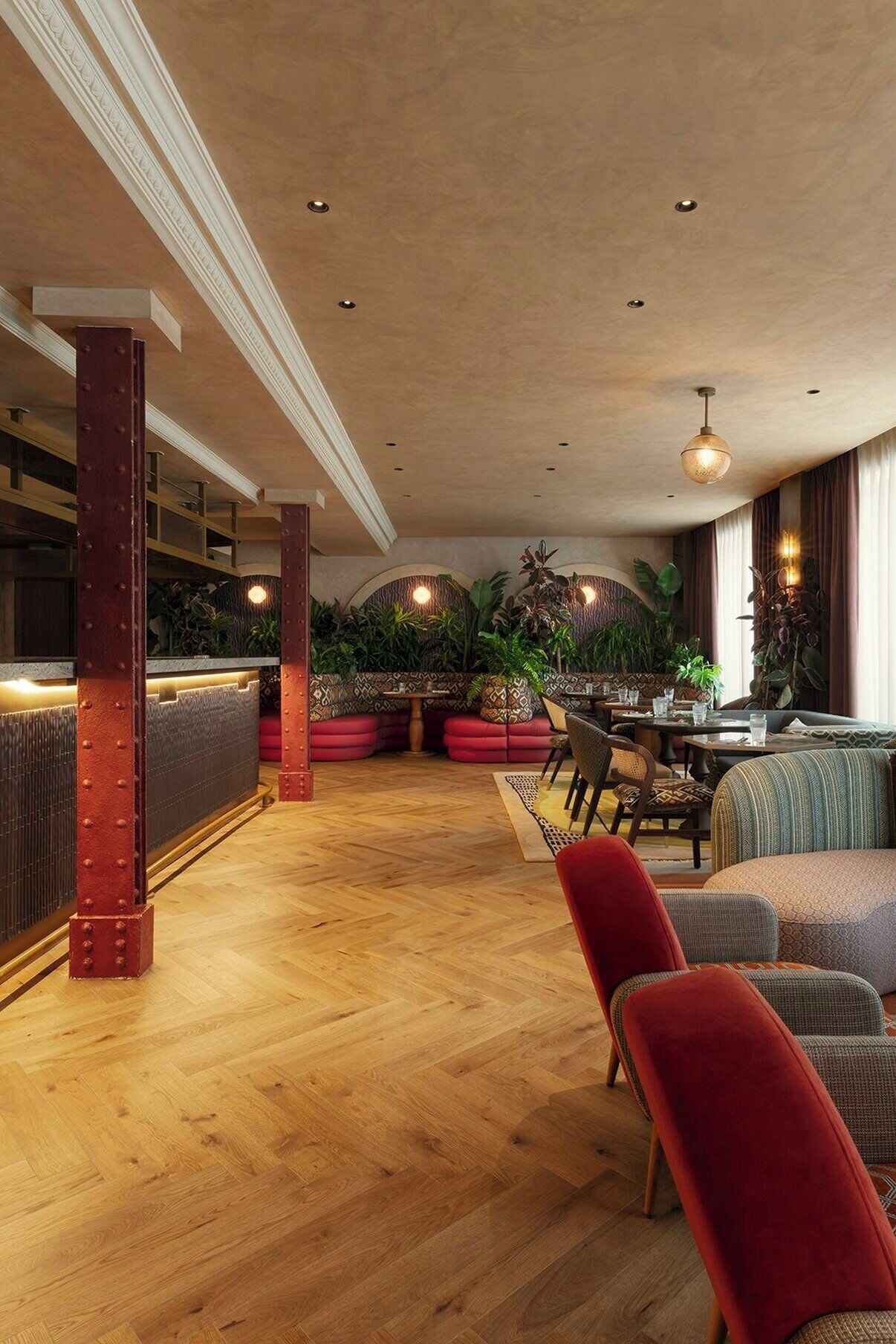 Ein großzügiger Innenbereich mit Holzboden, Sitzgelegenheiten und einer Bar mit roter Akzentwand.