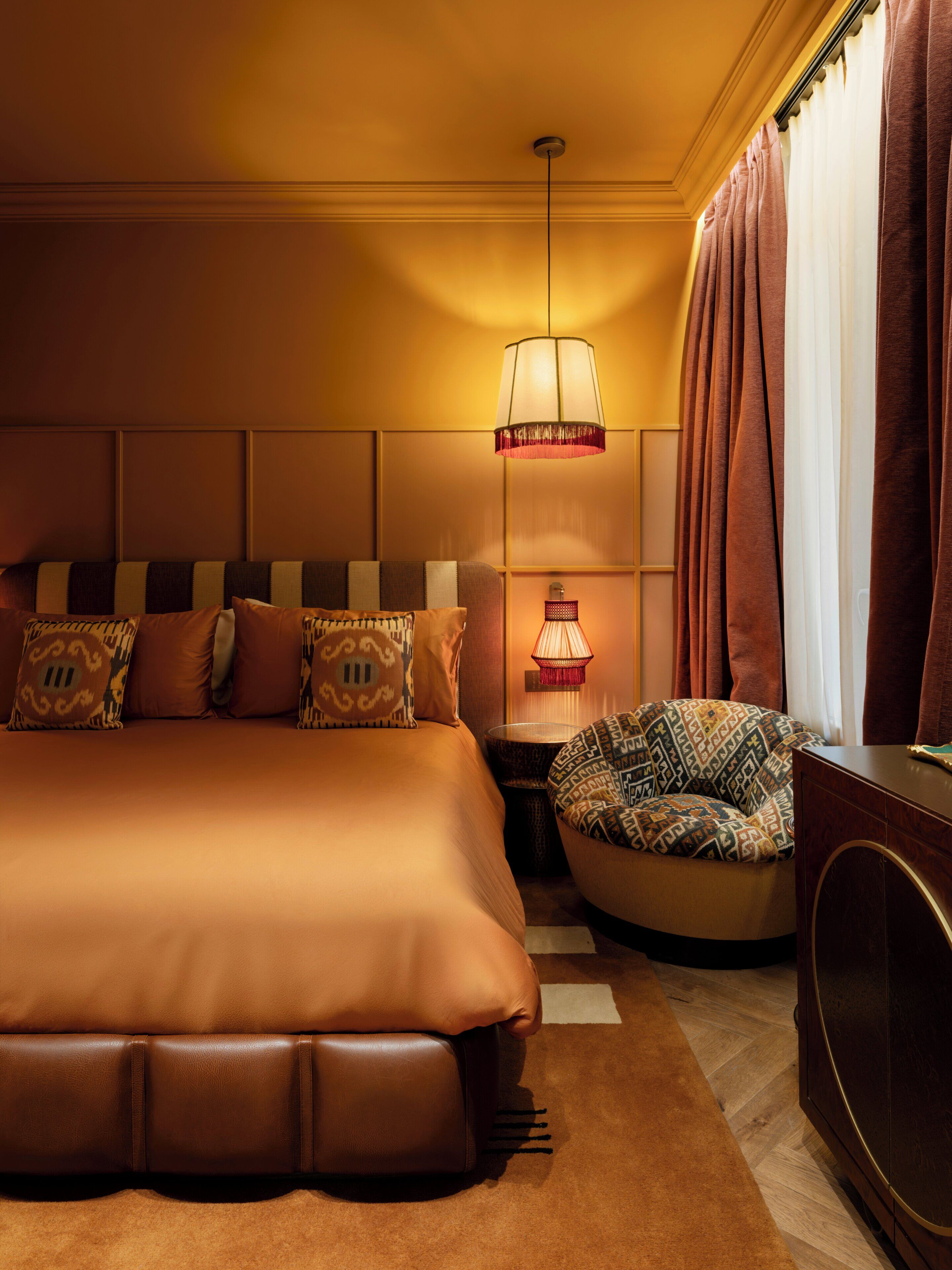 Una habitación de hotel con una cama grande, una mesita de noche con lámpara, una silla y un armario.