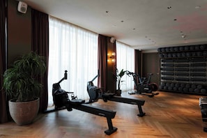 A gym with stationary bikes, a rowing machine, and a wall of dumbbells. - Nômade Temple Madrid (Madrid)