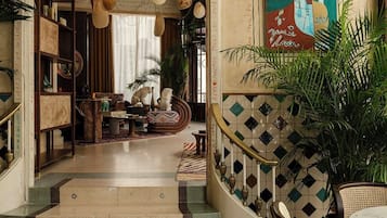 A spacious lobby with a central staircase, a large painting, and a variety of seating arrangements.