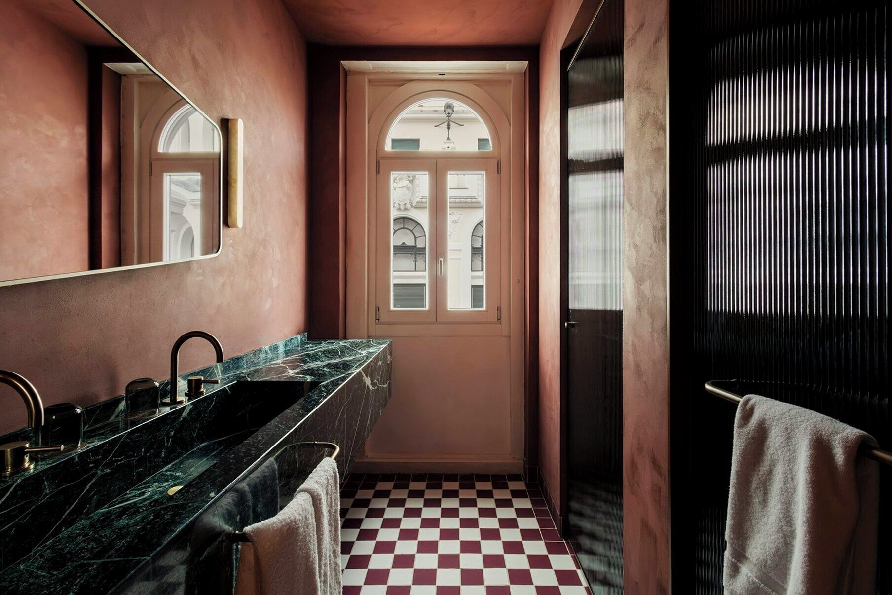 A bathroom with a checkered floor, a marble sink, and a mirror.