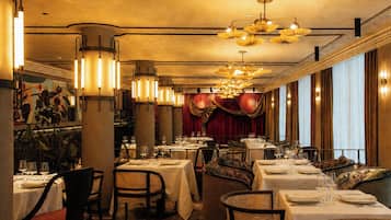 Interior de restaurante con varias mesas, sillas y diferentes lámparas.