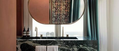 Un baño con encimera de mármol, un espejo grande y piso a cuadros.