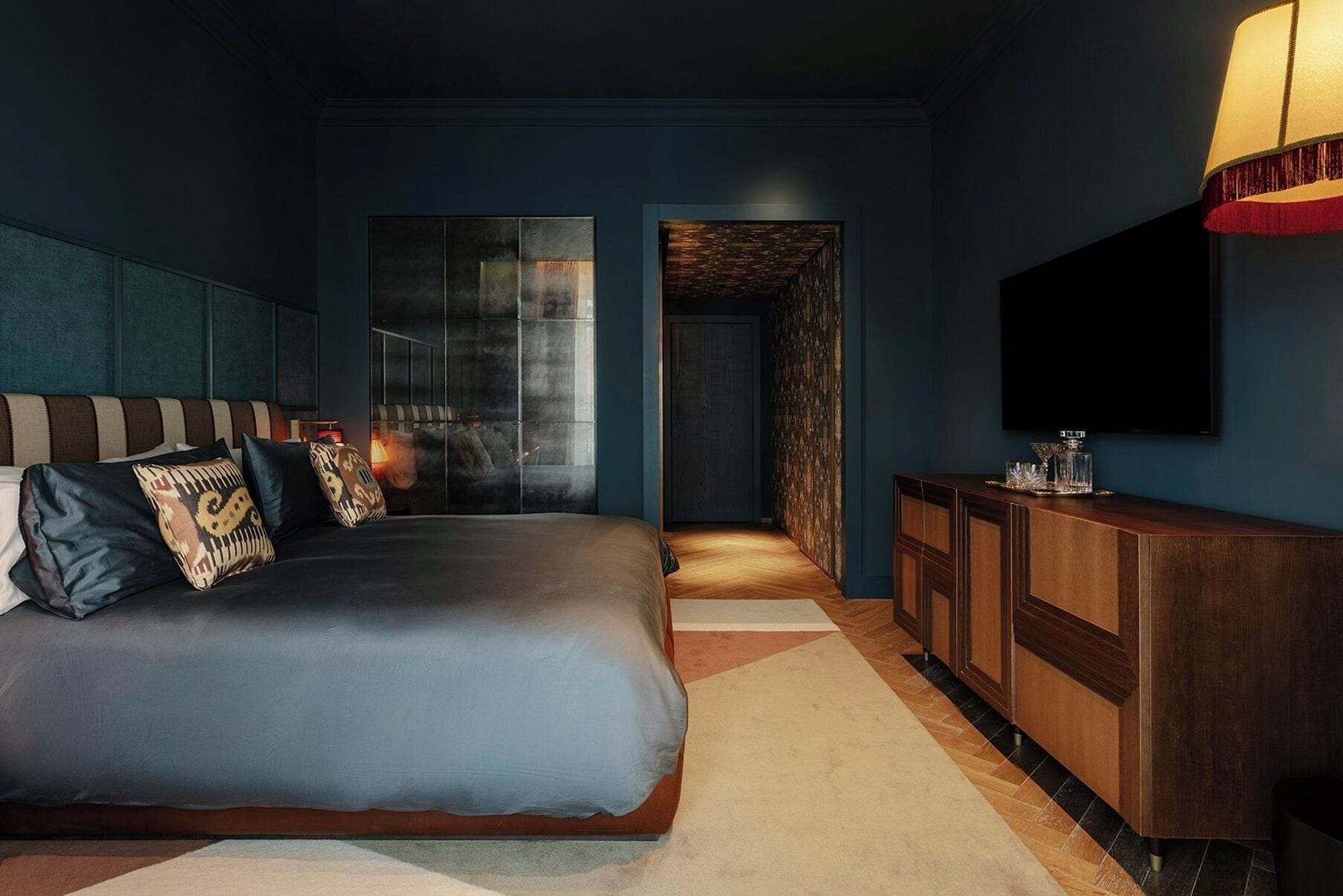 Une chambre d’hôtel moderne avec un grand lit, une commode en bois et un téléviseur fixé au mur.