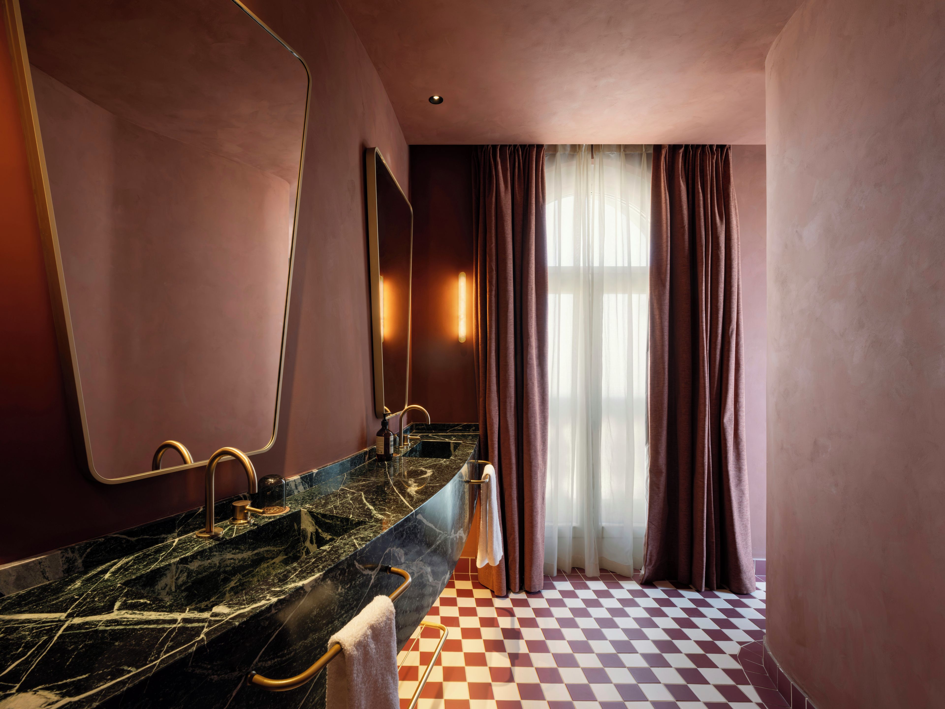 A bathroom with a checkered floor, a large mirror, and a marble sink.
