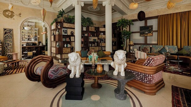 Uma sala de estar espaçosa com lareira, sofás de couro, mesa de centro e uma grande estante repleta de livros e objetos decorativos.