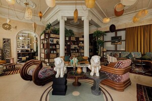 Ein geräumiges Wohnzimmer mit Kamin, Ledersofas, einem Couchtisch und einem großen Bücherregal voller Bücher und Dekoration.