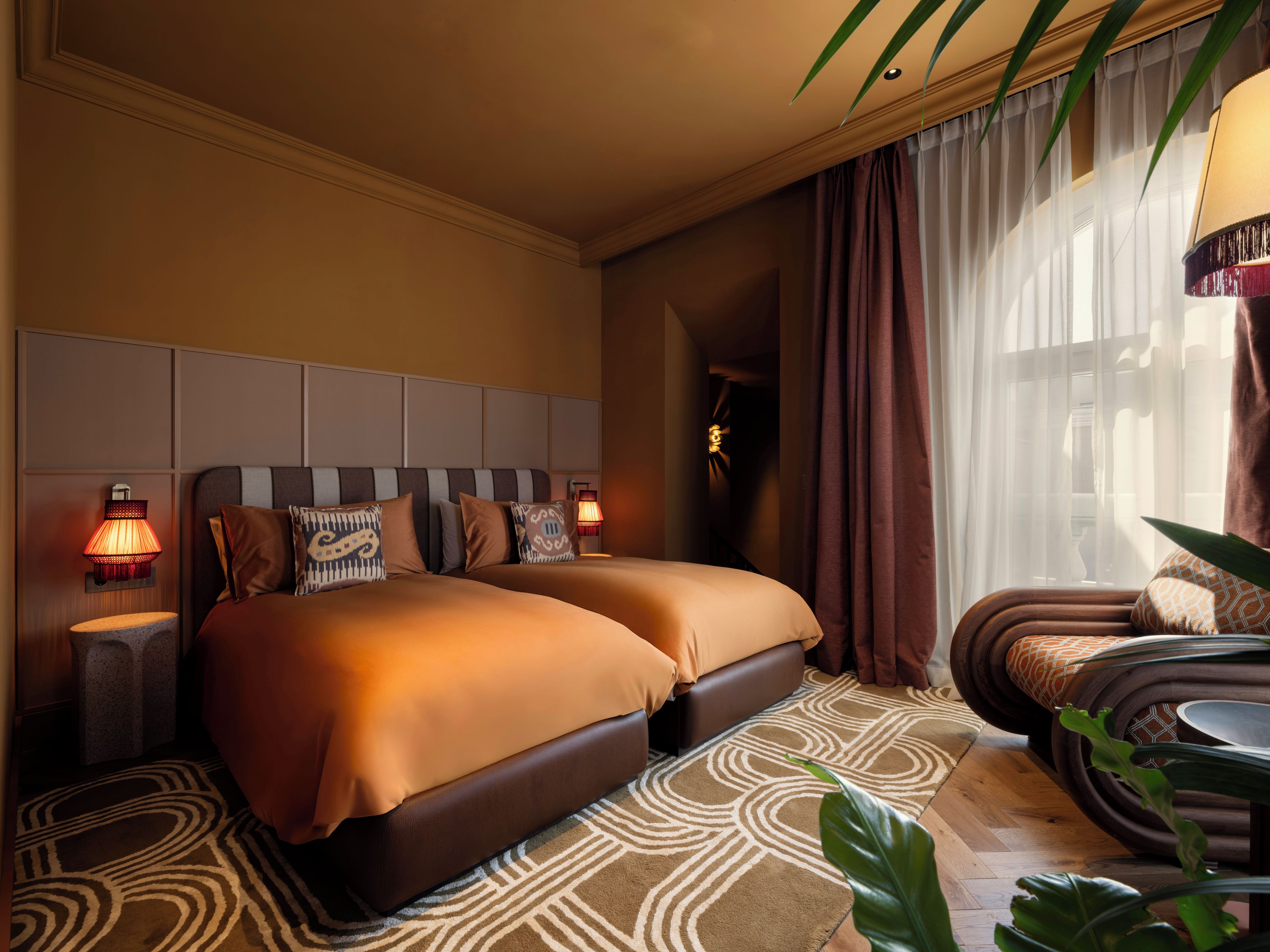 Una habitación de hotel con una cama grande, dos lámparas de noche, un sofá y una planta en maceta.