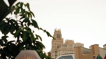 Un edificio con una torre de reloj y una cúpula. Cuenta con áreas de estar al aire libre y sombrillas.