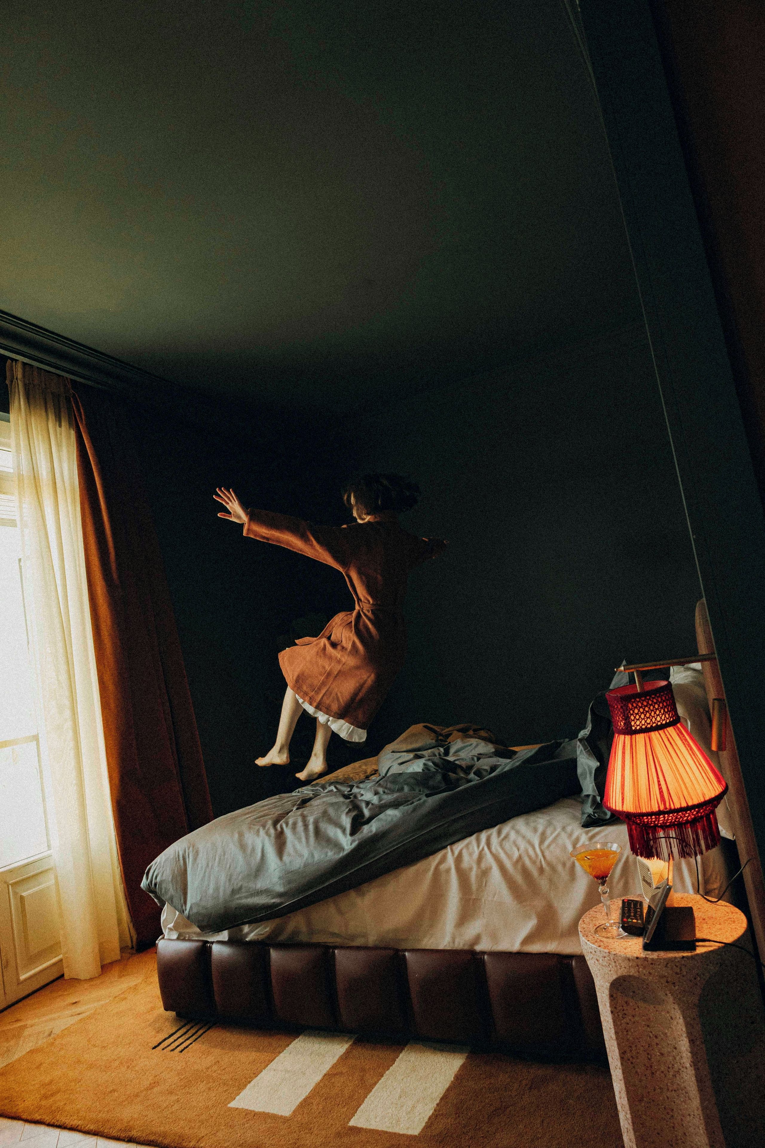 A room with a bed, a lamp, and a remote control on a side table.