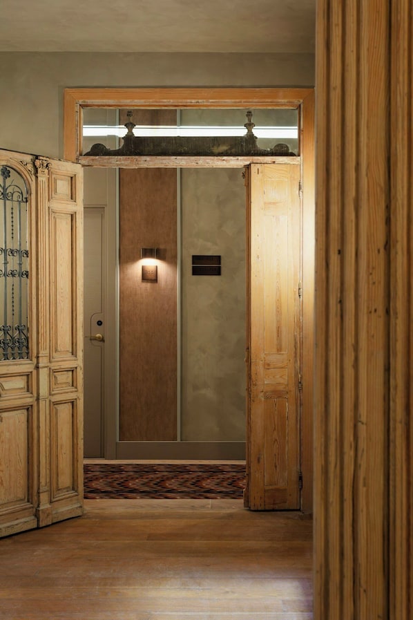 A wooden door with a number plate, a patterned carpet, and a wooden floor. - Nômade Temple Madrid (Madrid)
