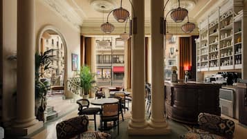 A hotel lobby with a bar area, seating arrangements, and a view of the street.