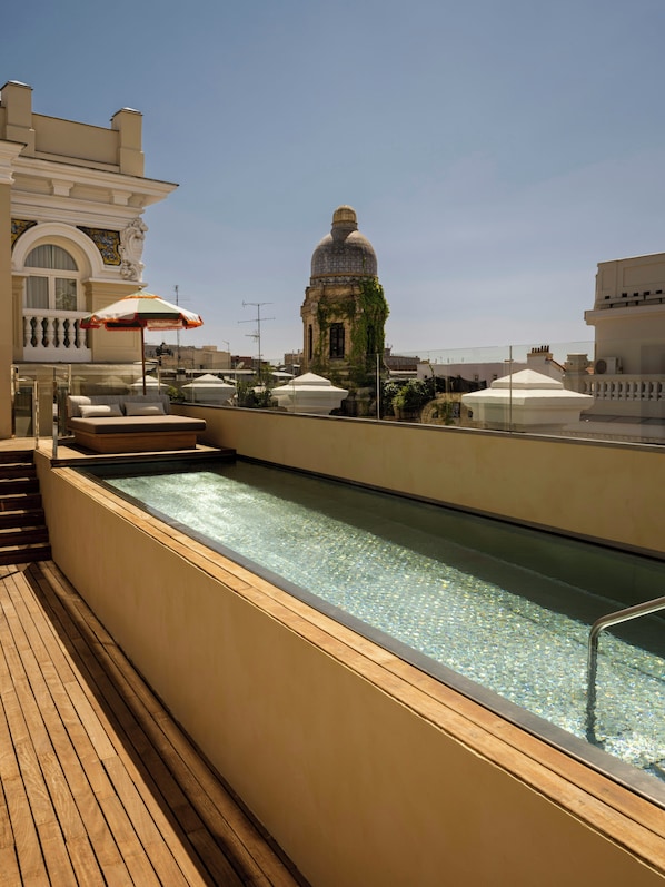 A rooftop pool area with a clear view of a historic building with a dome in the background. - Nômade Temple Madrid (Madrid)