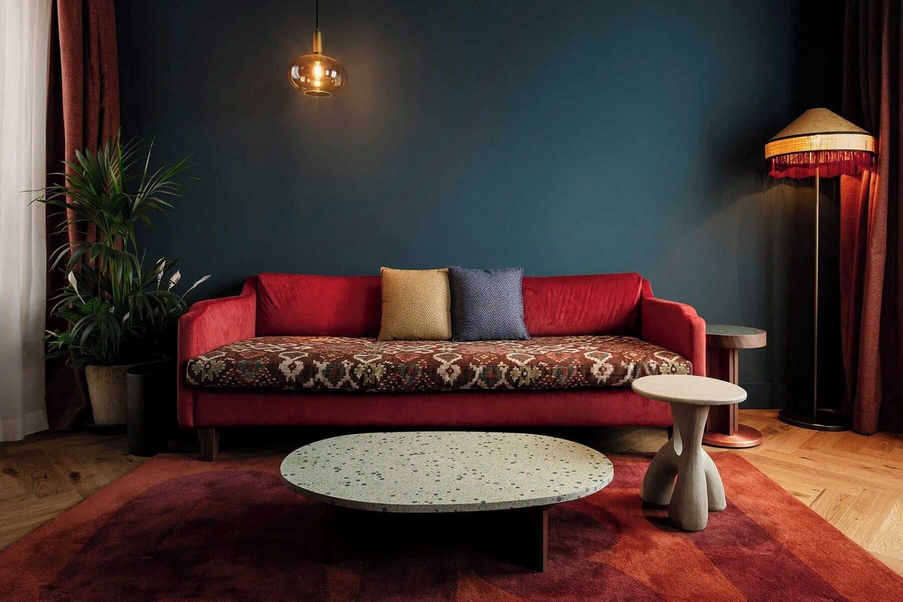 Un salon moderne avec un canapé rouge, une table basse ronde et un lampadaire.