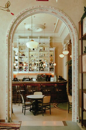 An interior with a bar area, shelves with bottles, and a seating arrangement. - Nômade Temple Madrid (Madrid)