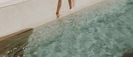 Eine Person steht am Pool, im Hintergrund eine Stadtansicht.