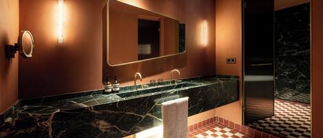 A modern bathroom with a marble sink, a large mirror, and a checkered floor pattern.