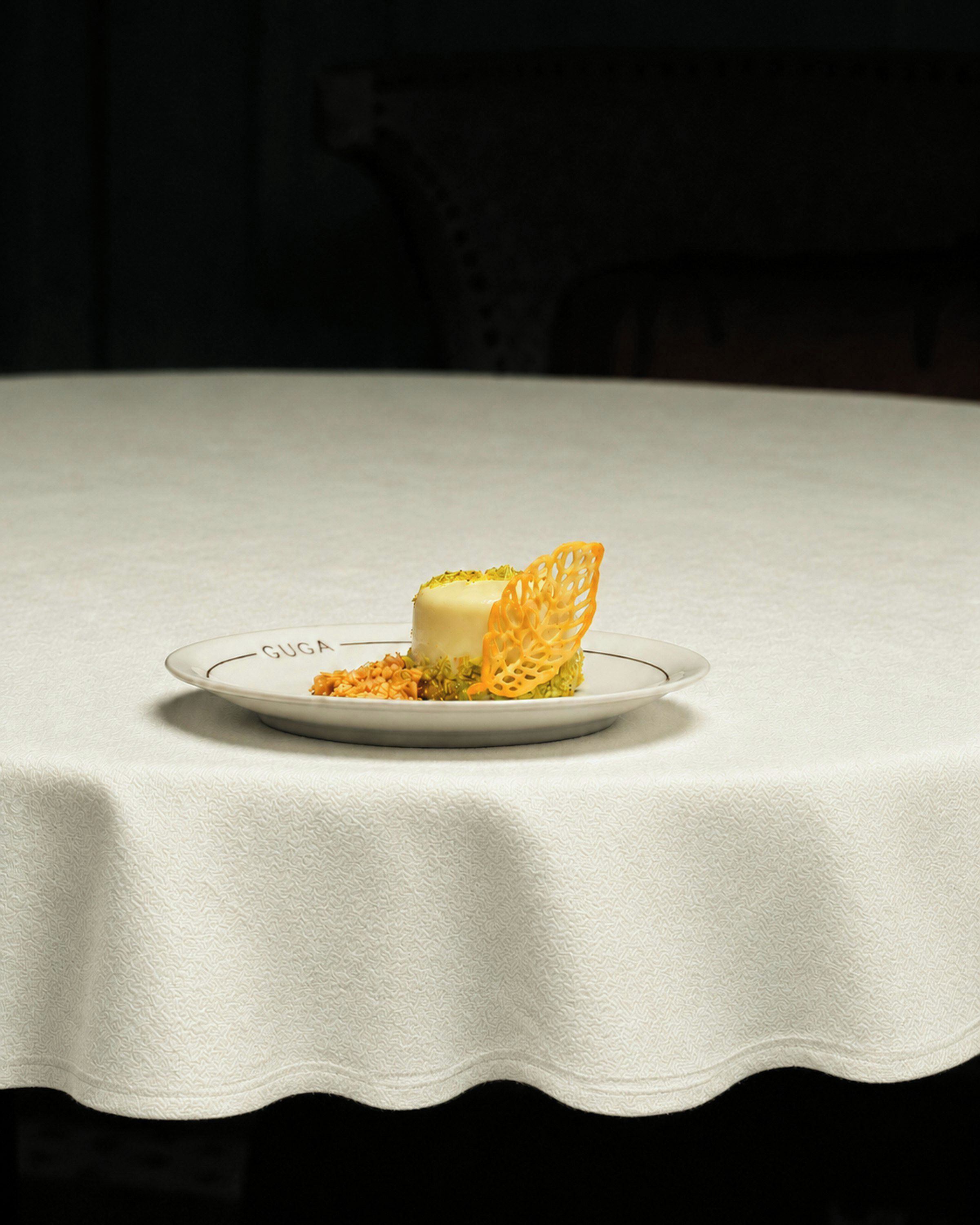 A plate with a dessert on a table with a white tablecloth.