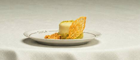 A plate with a dessert on a table with a white tablecloth.