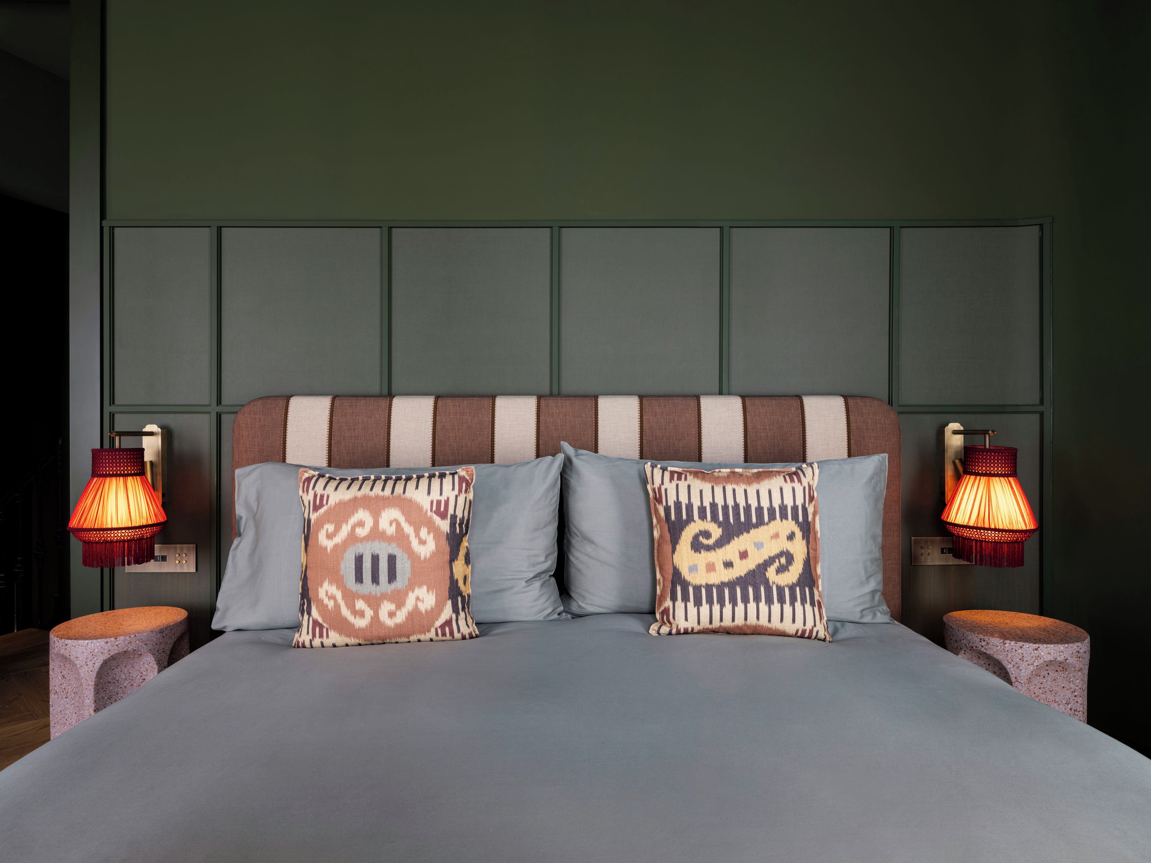 A bed with two pillows, two nightstands, and two wall-mounted lamps.