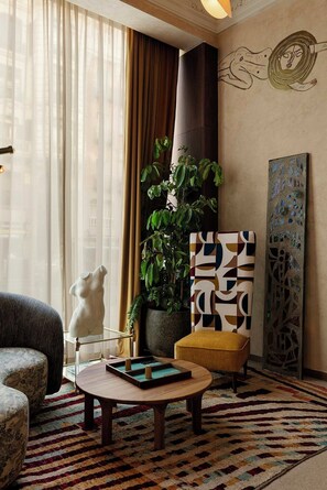 A modern living room with a sofa, a coffee table, a potted plant, and abstract wall art. - Nômade Temple Madrid (Madrid)