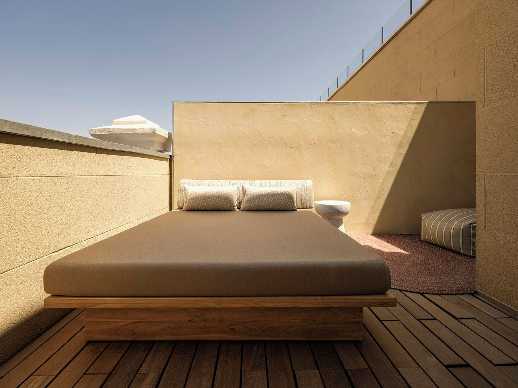 Un lit simple avec un cadre en bois et un matelas posé sur une plateforme en bois.