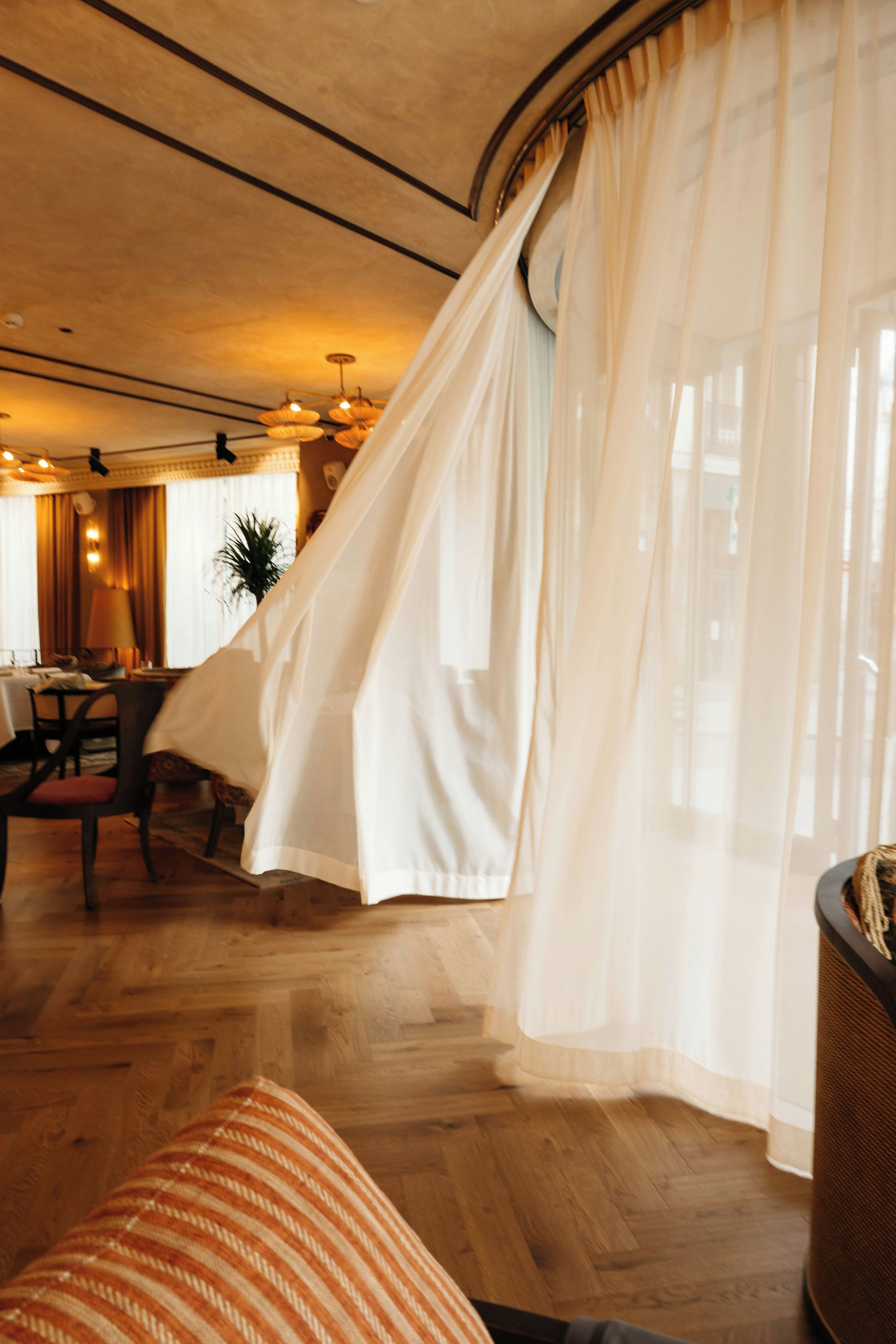 Una habitación con cama, una silla, una mesa y una ventana con cortinas ligeras.