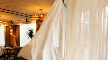 Una habitación con cama, una silla, una mesa y una ventana con cortinas ligeras.
