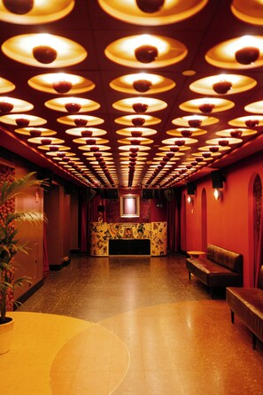 Un pasillo con pared decorada y una zona de estar con un banco.