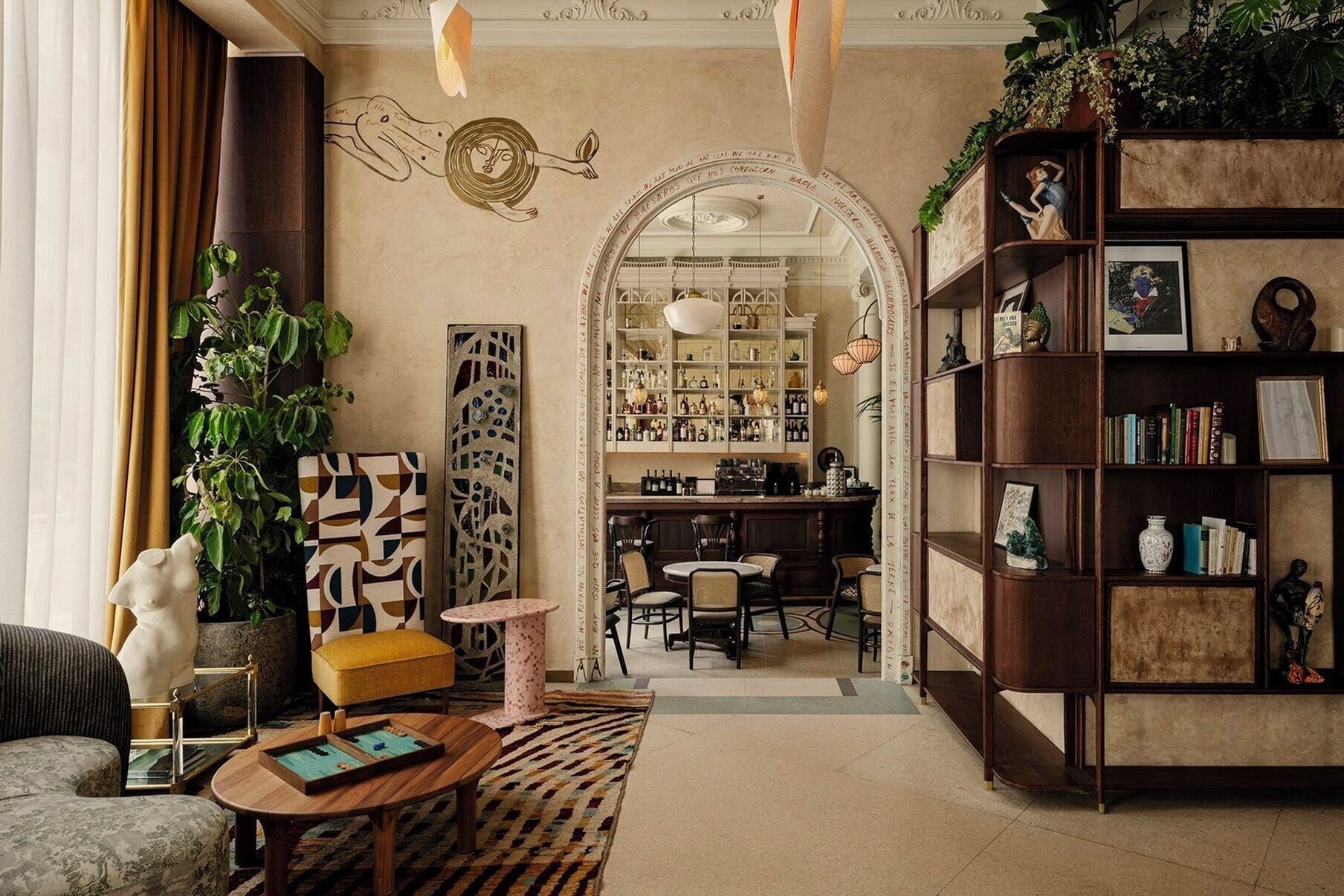 A cozy living room with a bar area, bookshelves, and a decorative archway.