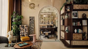 A cozy living room with a bar area, bookshelves, and a decorative archway.