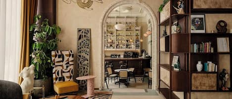 A cozy living room with a bar area, bookshelves, and a decorative archway.