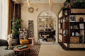 A cozy living room with a bar area, bookshelves, and a decorative archway. - Nômade Temple Madrid (Madrid)