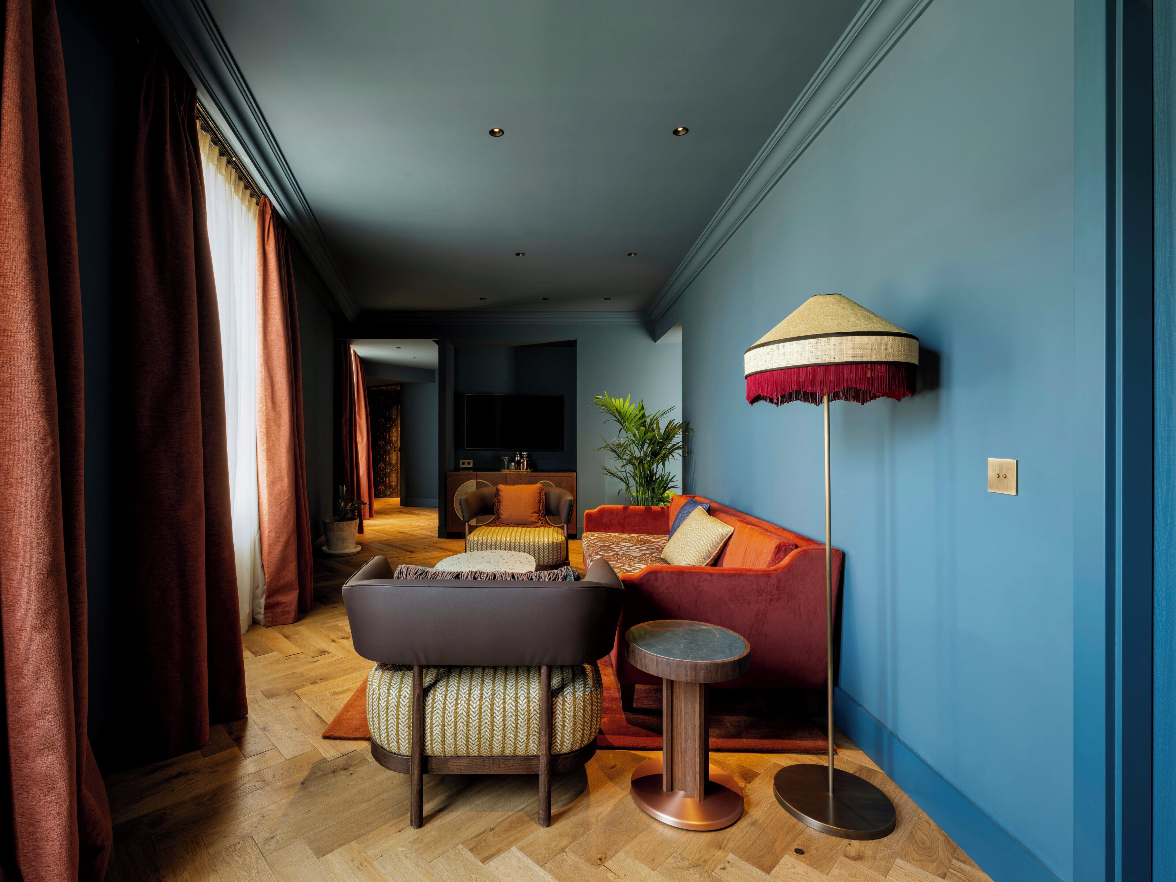 A modern living room with a sofa, ottoman, floor lamp, and a television.