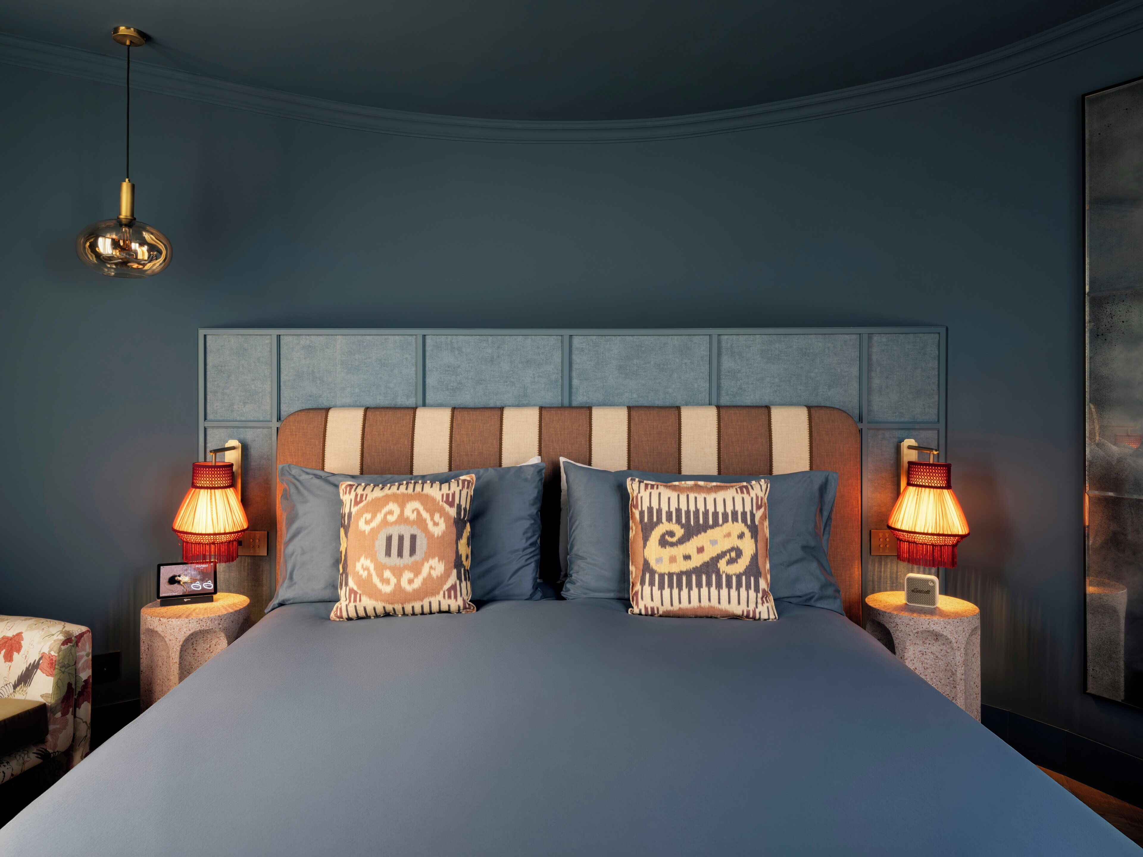 A bedroom with a large bed, two bedside lamps, a wall-mounted light, and a decorative pillow.