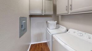 A laundry room with a washing machine, dryer, and stacked cabinets. - I241 - Apt|Patio|10mi to Convention Ctr|Sleeps 4 (Irving)