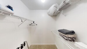 Ein kleiner Raum mit weißen Wänden, einem einzelnen weißen Heizkörper, einem weißen Deckenventilator und einem weißen Regal mit gefalteten Handtüchern.