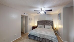 Ein Schlafzimmer mit einem gepolsterten Kopfteil, einem Deckenventilator und zwei Nachttischlampen.