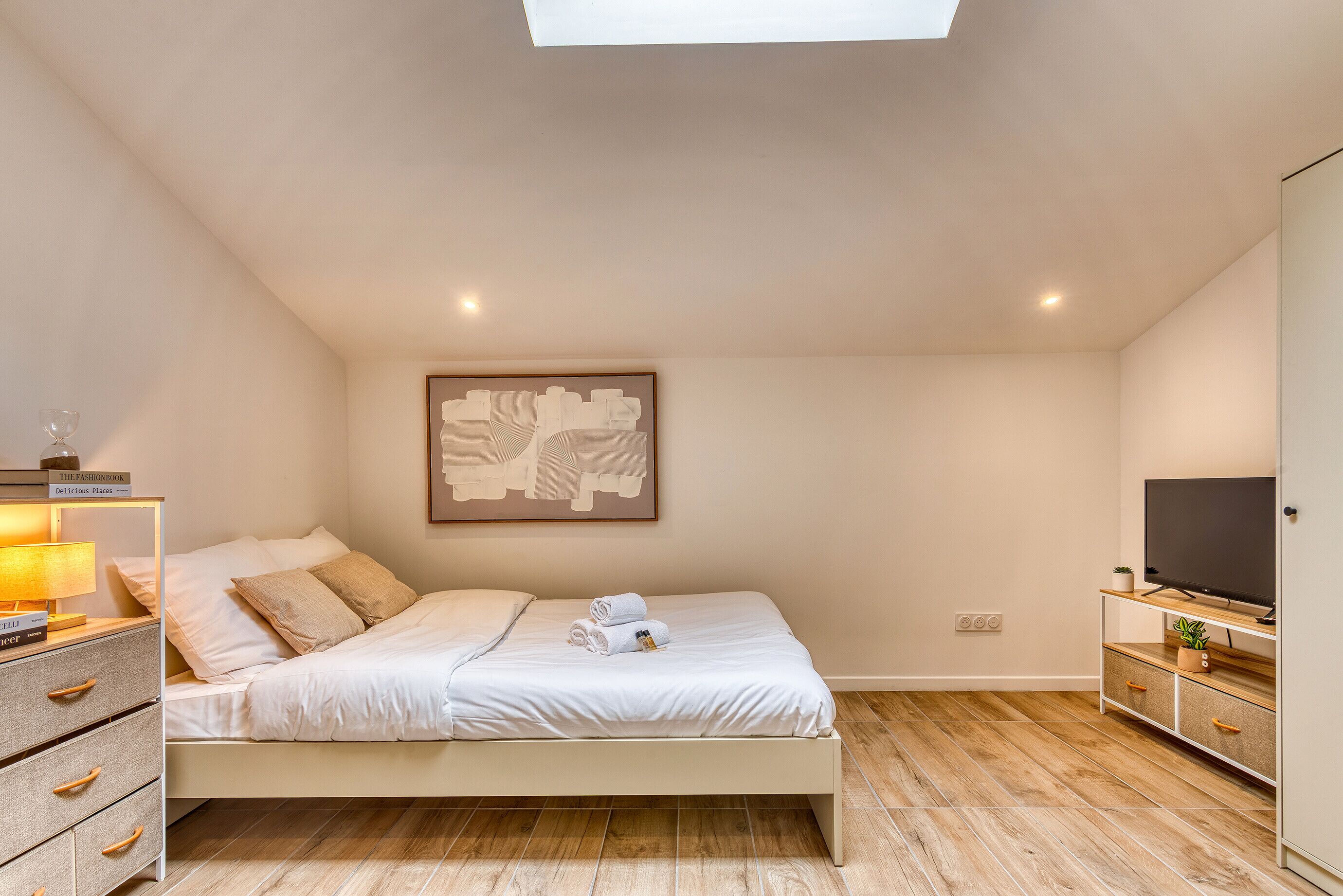 Ein modernes Schlafzimmer mit Bett, Nachttisch, Fernseher und einer Wandkunst mit einer Weltkarte.