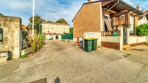 A narrow street with buildings on either side, a visible trash bin, and a clear sky. - Le Factory - Studio contemporain - Proche métro B (Oullins-Pierre-Bénite)