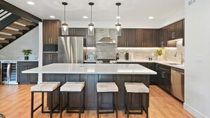 A modern kitchen with a large island, dark wood cabinets, stainless steel appliances, and pendant lighting. - New Ski/Summer Home (Cottonwood Heights)