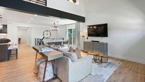 A modern living space with a dining area, a sofa, a TV, and a staircase. - New Ski/Summer Home (Cottonwood Heights)