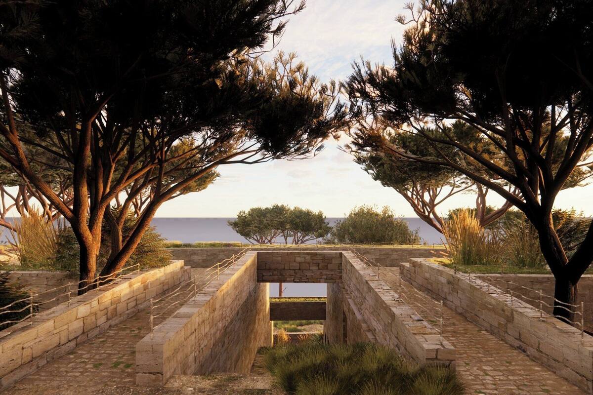 A stone pathway leading to a view of the sea, surrounded by trees and a stone wall.
