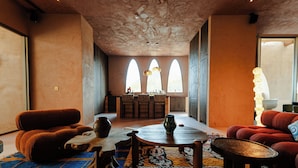 Een ruime woonruimte met een hoge plafond, een houten eettafel en een groot raam met uitzicht.