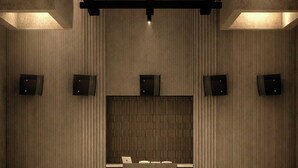 Un vestíbulo amplio con mostrador de recepción, paneles de madera verticales e iluminación empotrada en el techo.