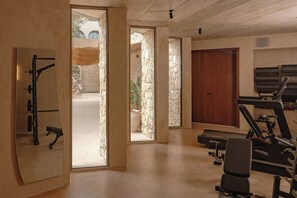 Une salle de sport équipée de matériel d’exercice, d’un banc et d’une porte donnant sur un espace extérieur.