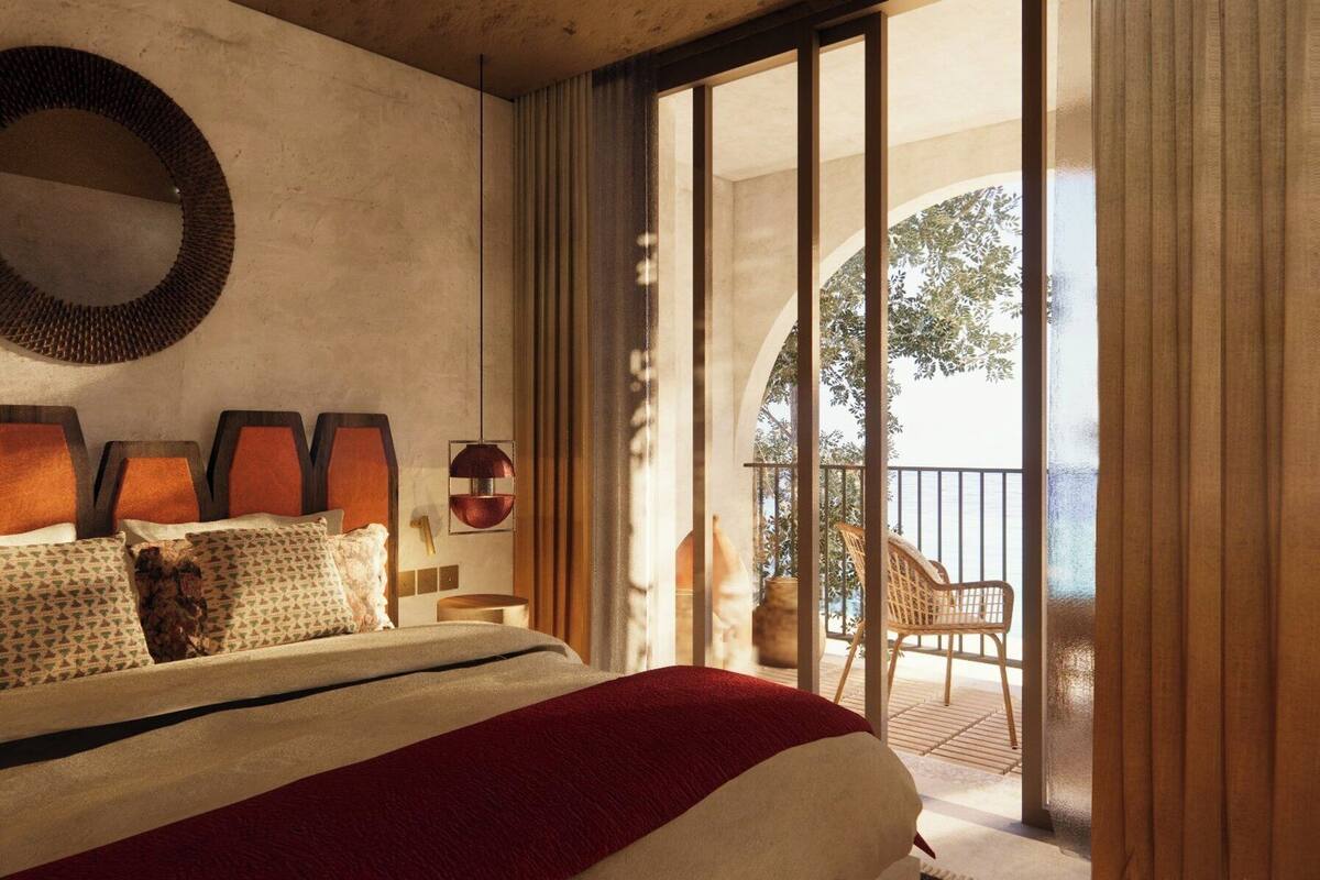 A bedroom with a large bed, a circular mirror, and a view of a balcony with outdoor furniture.