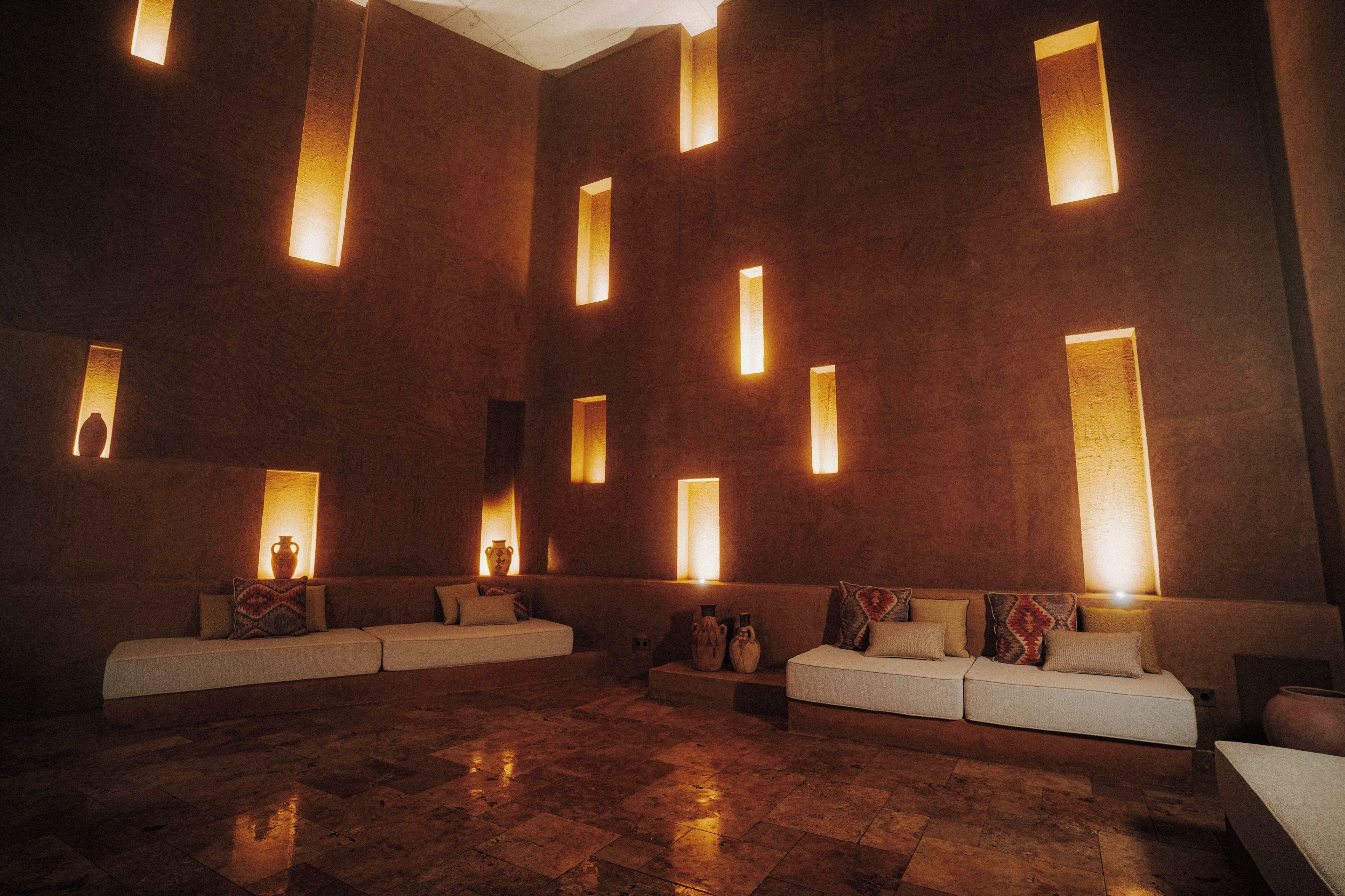A spacious lobby with a modern design, featuring a large seating area with sofas and a patterned rug.